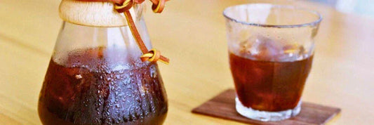 Cold brew servido en vaso y jarra con hielo sobre mesa, café frío ideal para verano.